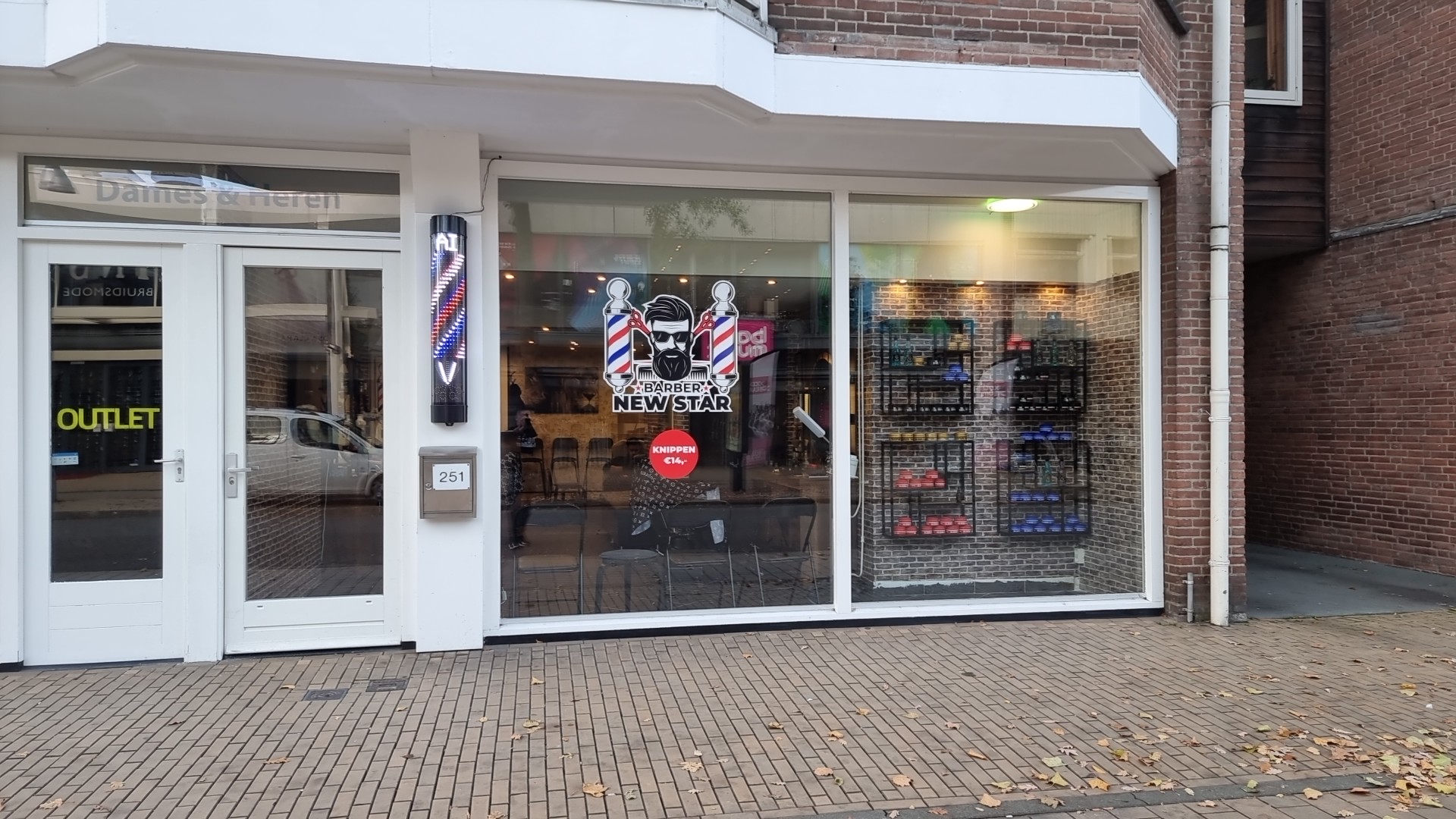De gevel van Barber Newstar overdag, met de barberpaal naast de deur en de sticker op de ruit