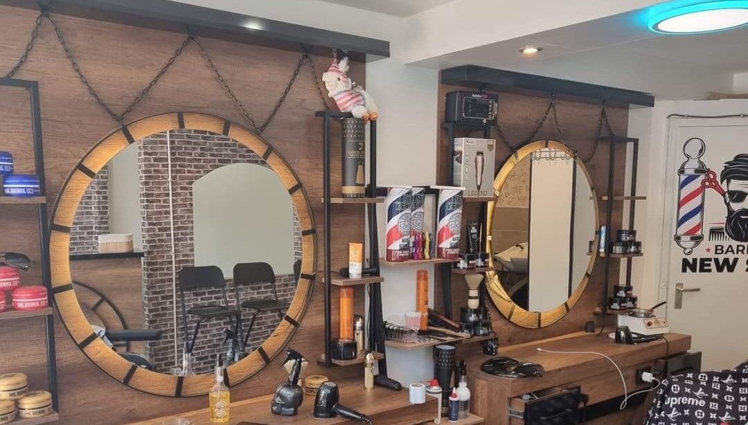 Binnen bij Barber Newstar: ronde spiegels met houten rand, schappen met producten en een barberpaal op de muur